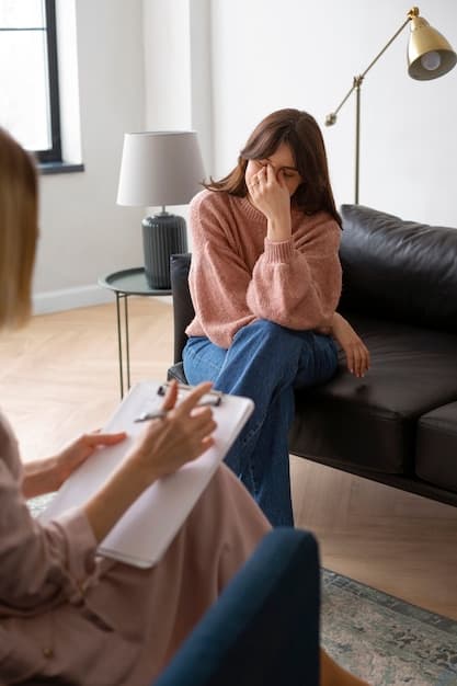 A woman seated in therapy while speaking with a counselor in a calm office.