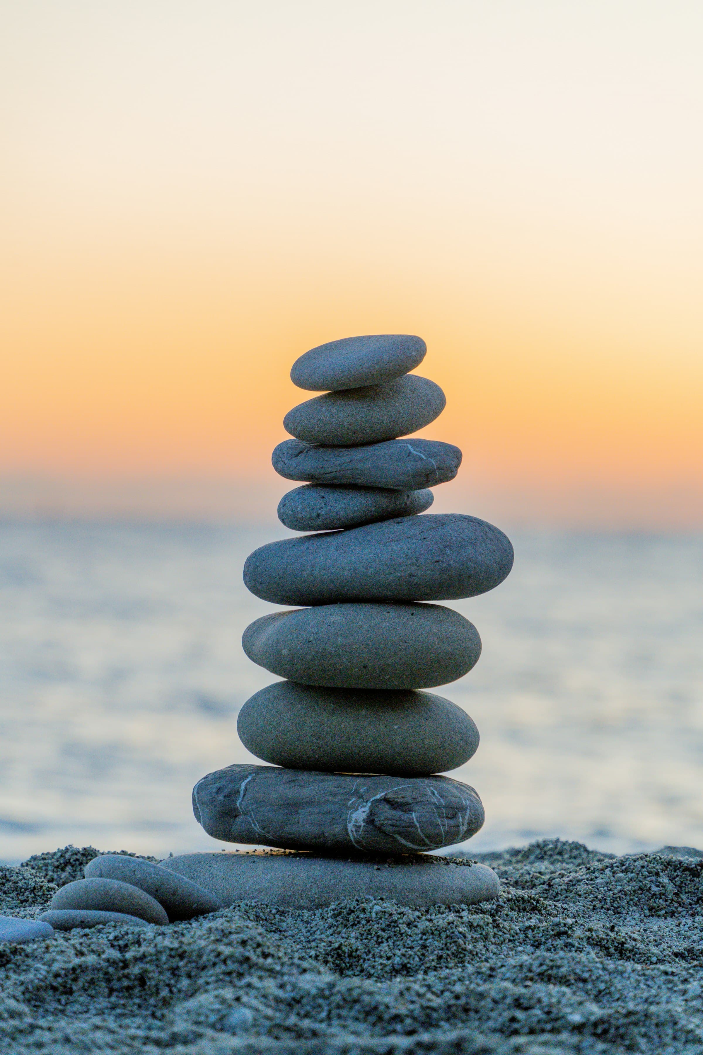 Balanced stones on a quiet shoreline at sunset.
